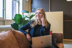 Professionally dressed female presenting person using phone and computer